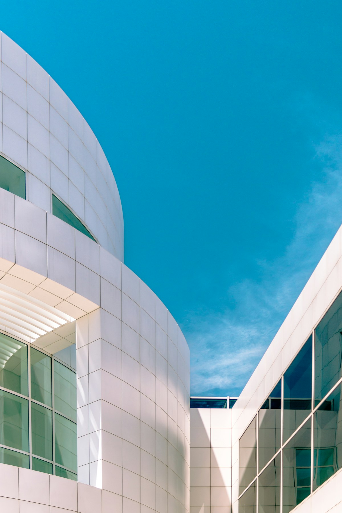 Sculptural white architecture opening toward a clear blue sky